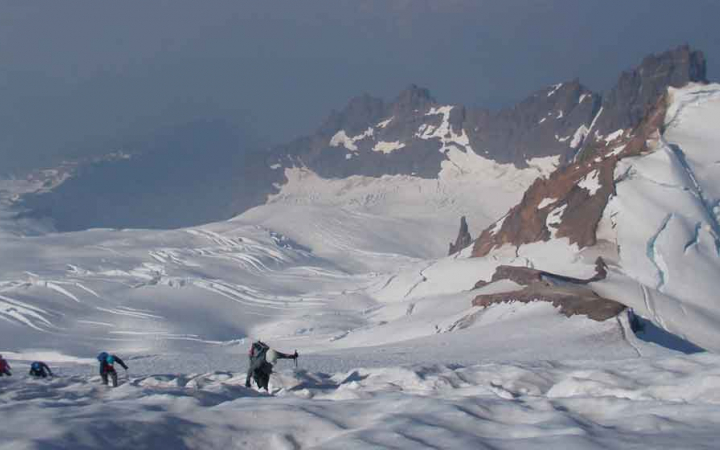 four students navigate a snowy mountainous landscape